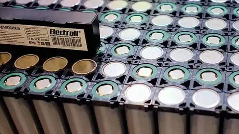 Cylindrical lithium-ion battery cells in a black plastic tray with an Electroll battery pack label nearby