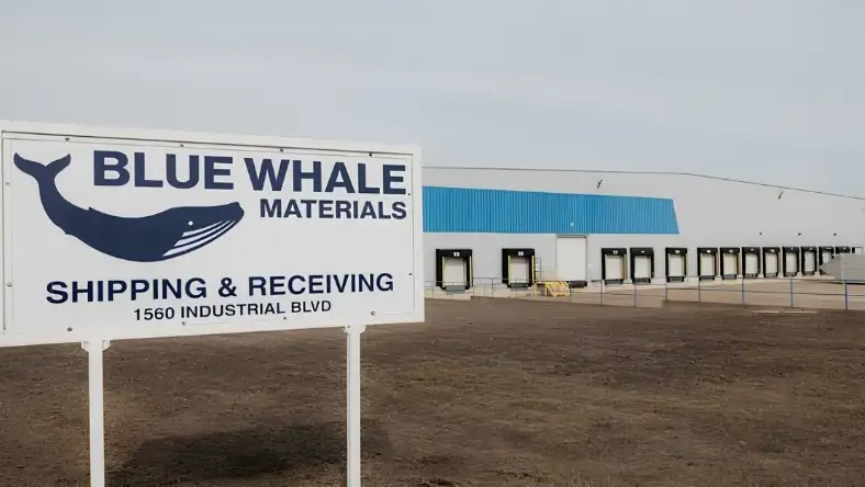 Blue Whale Materials facility sign in front of a large industrial warehouse with multiple loading dock doors